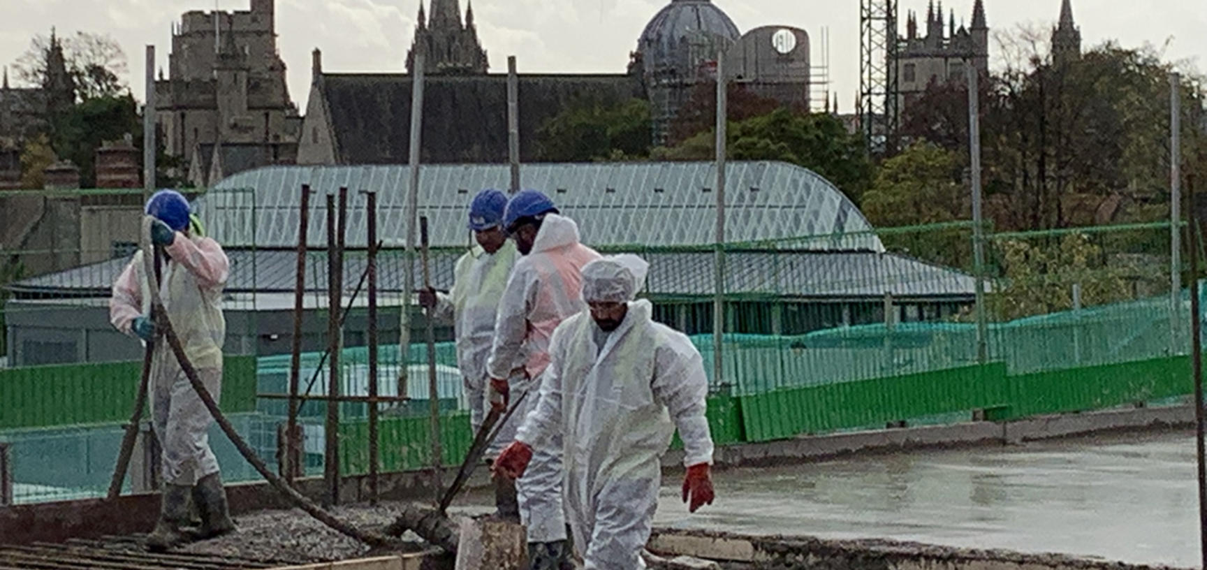 Workers in white protective suits pouring concrete