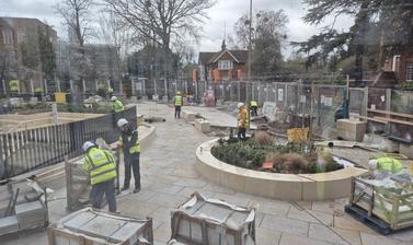 View from inside the Life and Mind Building, towards landscape works going on outside. Construction workers moving materials on pallets and planting shrubs