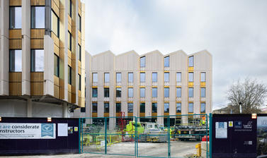 Side view of outside of the Life and Mind Building in November, with security fencing/gates in the foreground