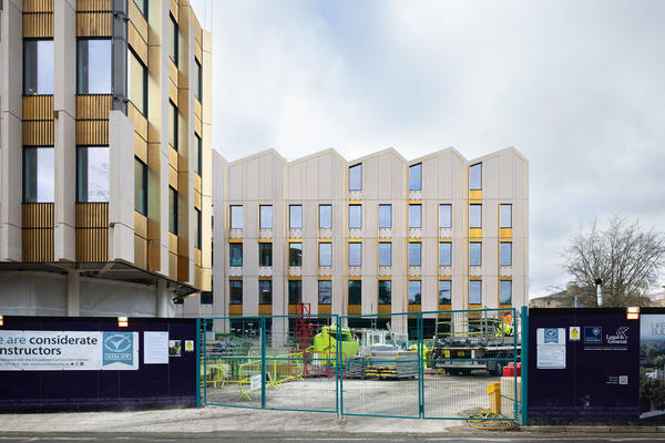 Side view of outside of the Life and Mind Building in November, with security fencing/gates in the foreground